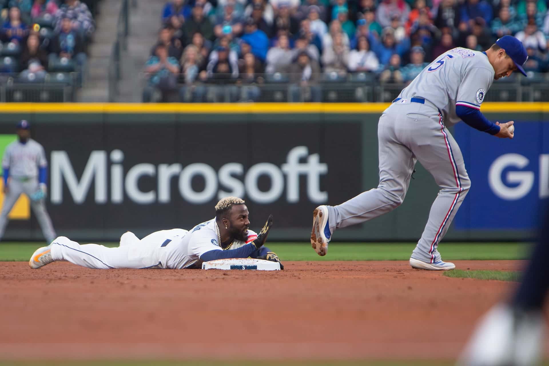 Mariners runner flat on the dirt after sliding into second base as a defender chases the play