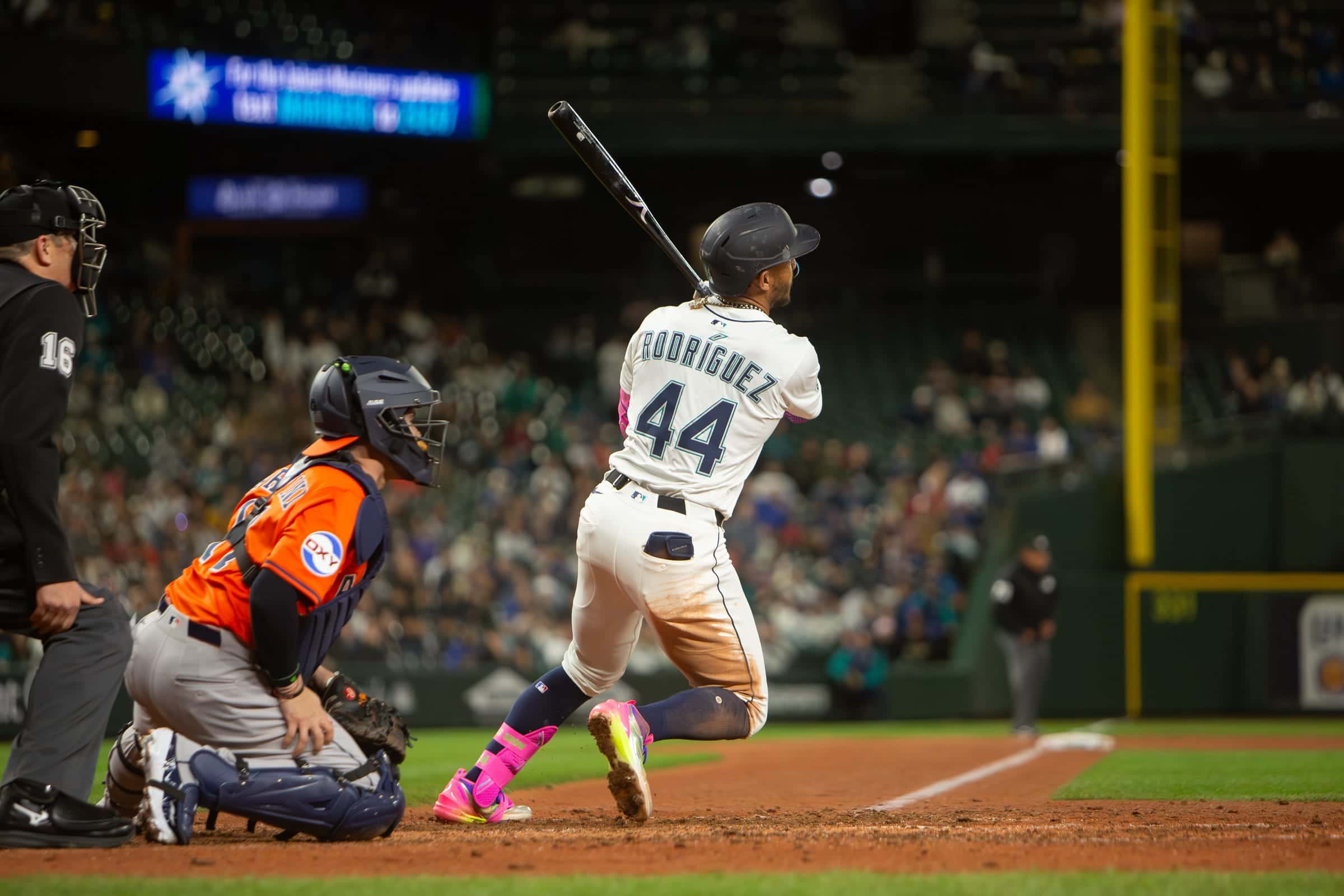 Mariners outfielder Julio Rodriguez, number 44, swinging as the catcher and umpire look on