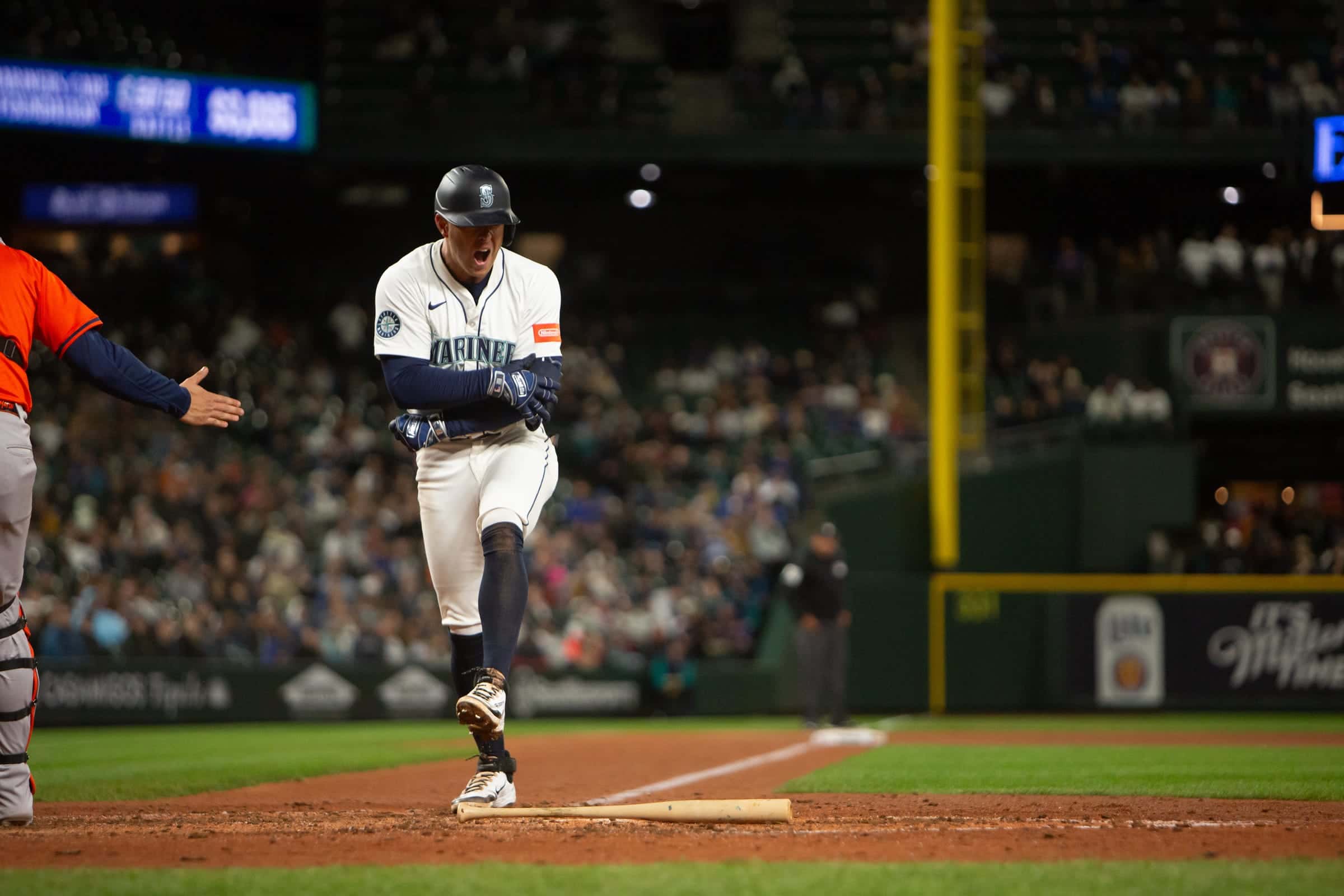 Mariners hitter breaking out of the box toward first base during a night game