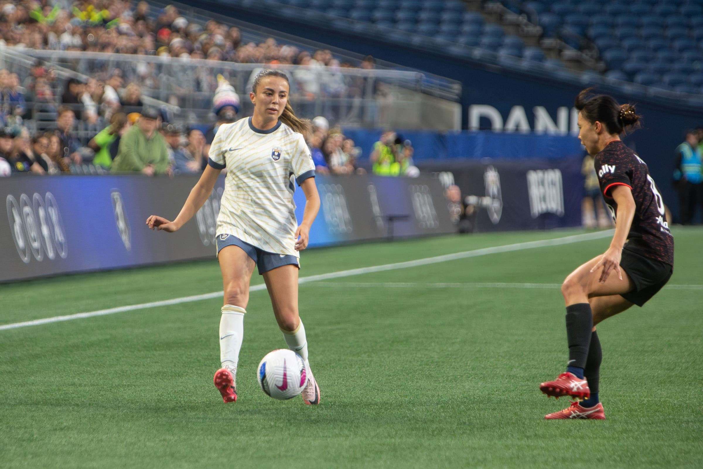 Reign player carrying the ball as a defender backpedals