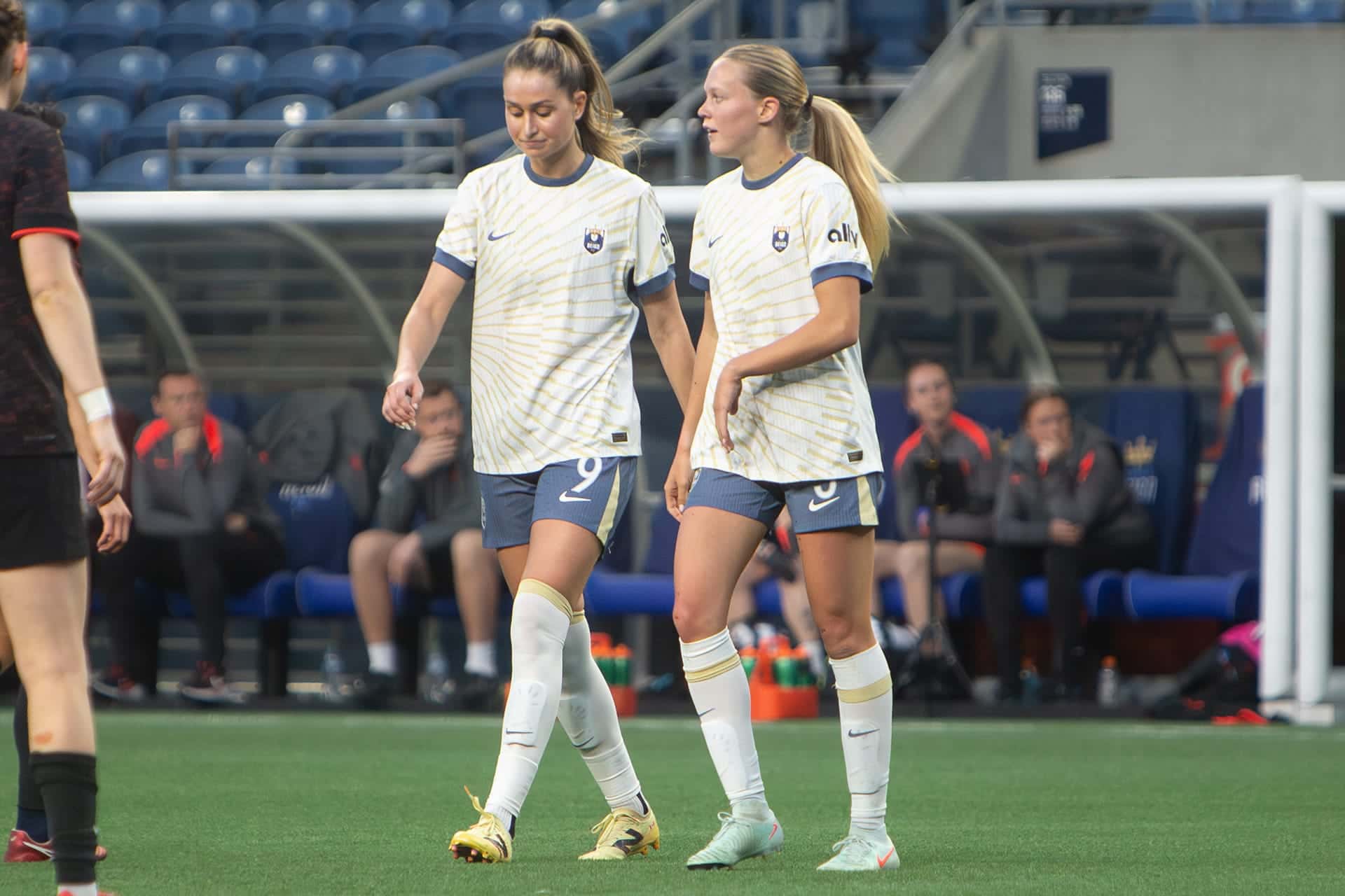 Two Reign players standing together near the goal during a break in play