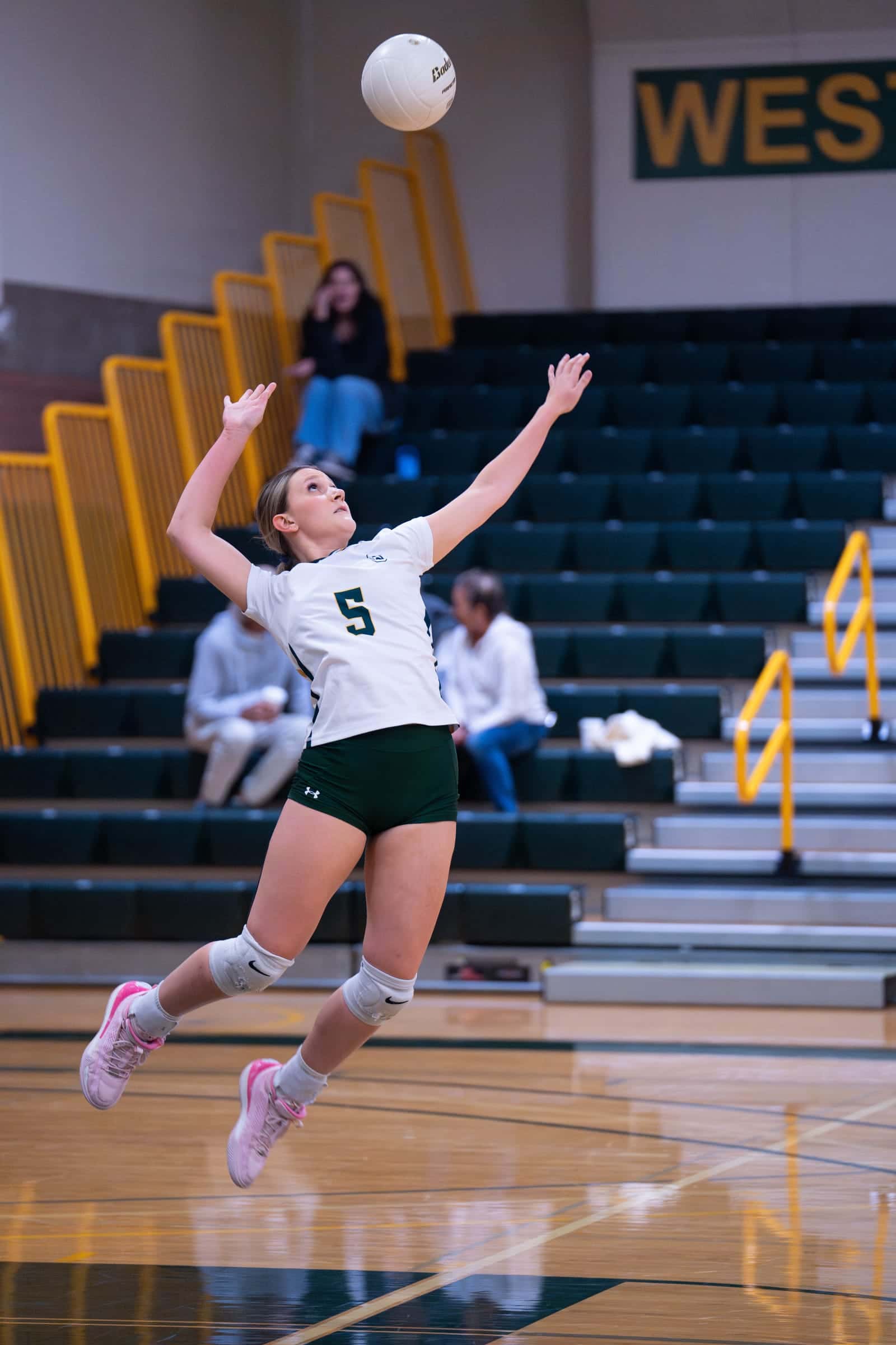 Shoreline volleyball player, number 5, rising into a jump serve