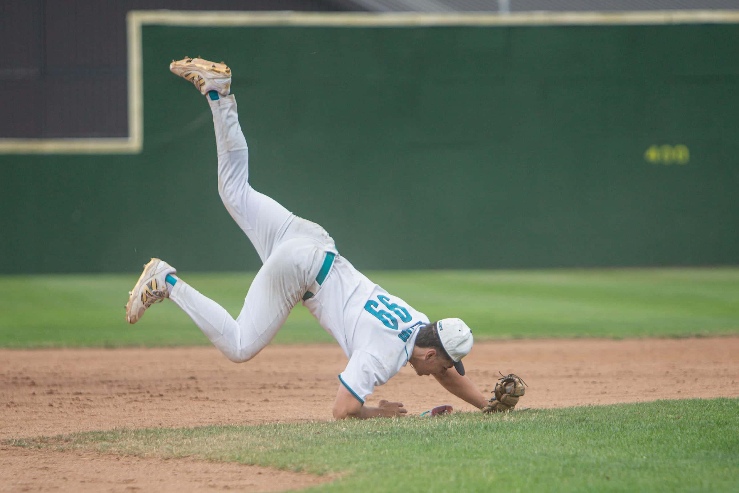 Showcase infielder upside down in the air, landing after a diving play