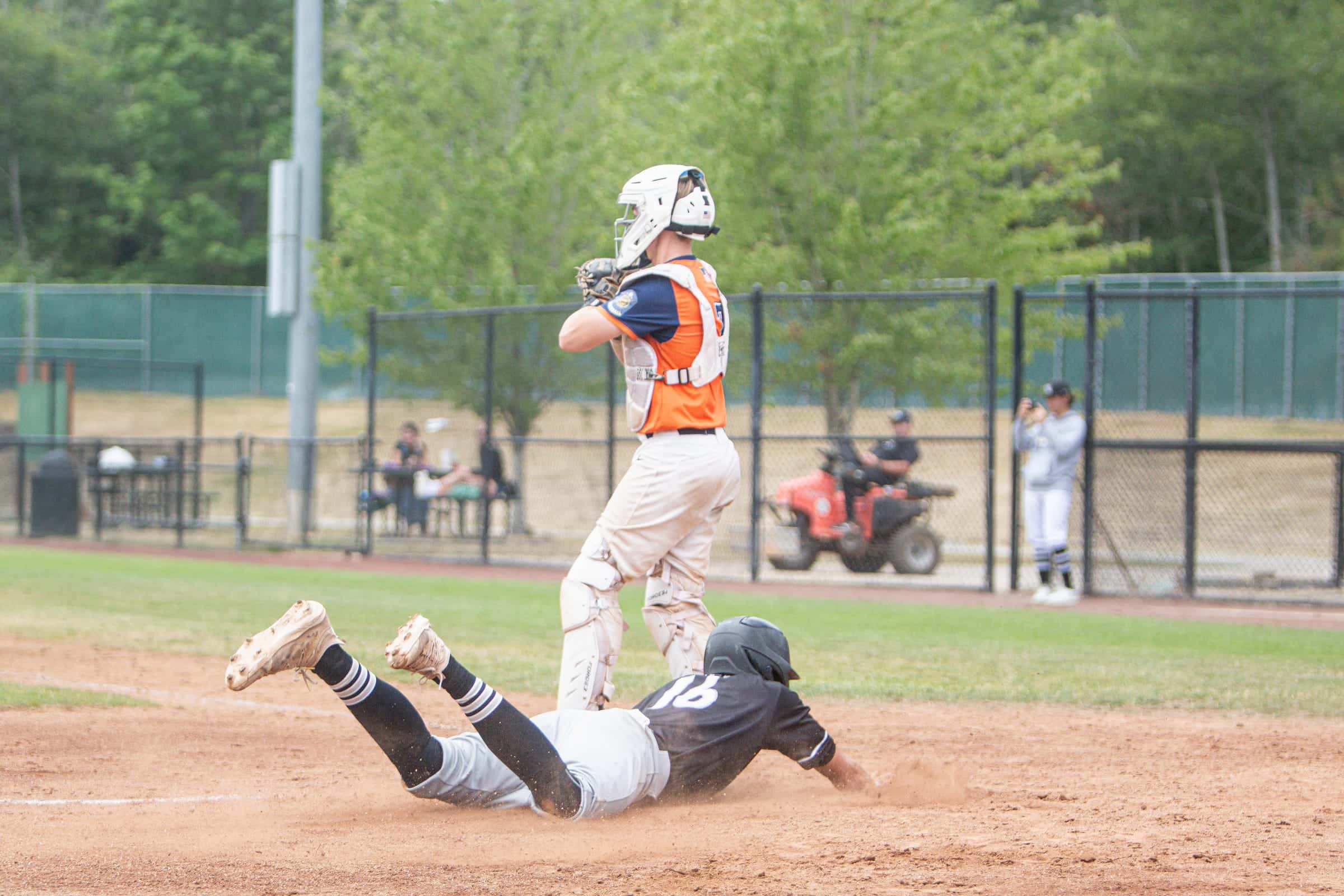 Runner diving headfirst back to the bag as the fielder waits for the throw