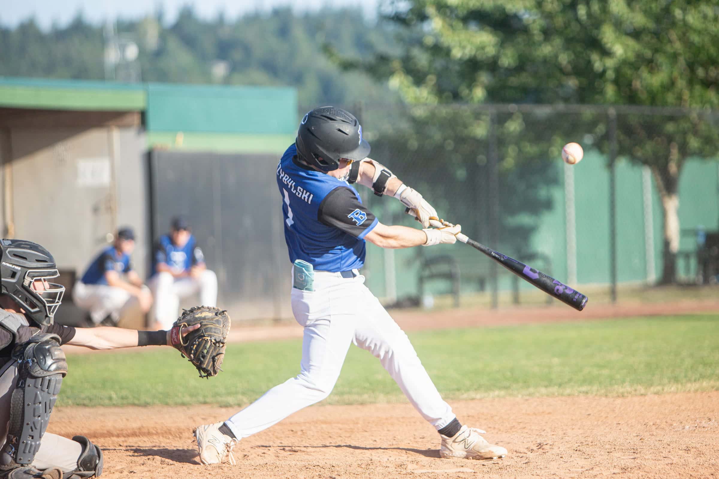 Hitter in blue making contact with the ball leaving the bat