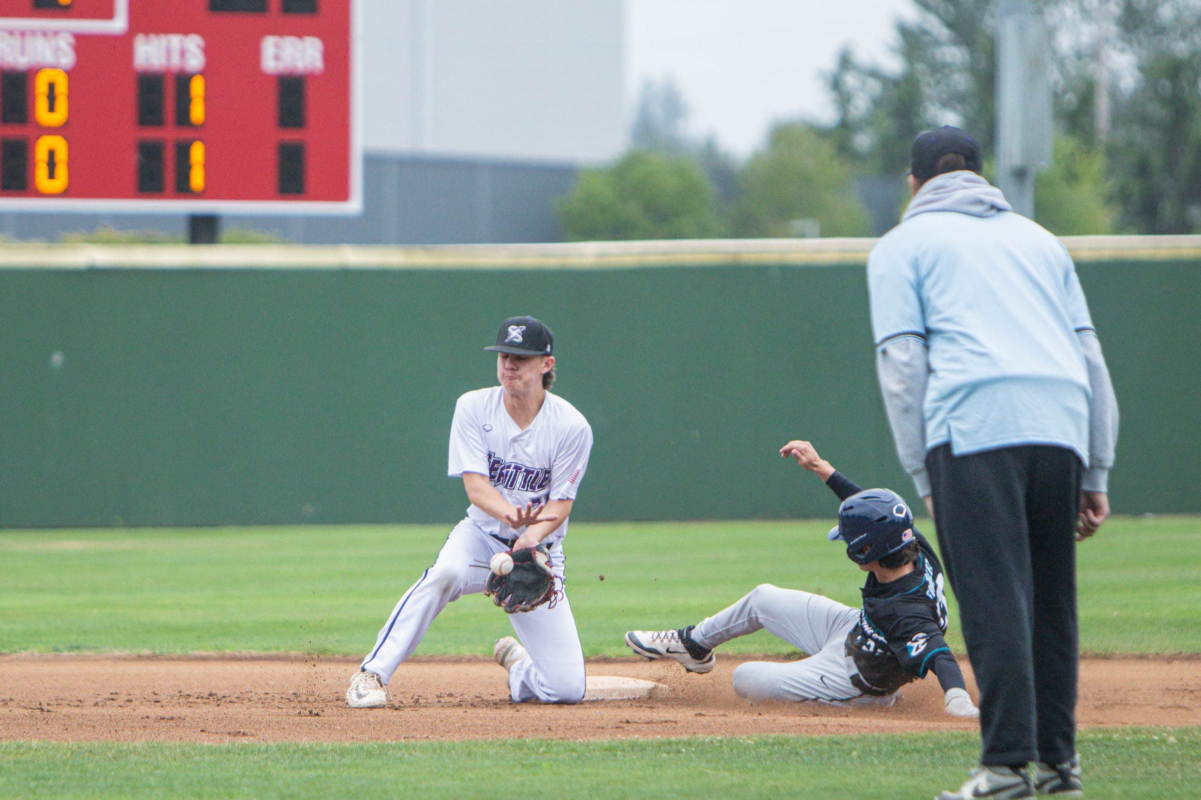 Infielder applying a tag on a sliding runner as the umpire watches