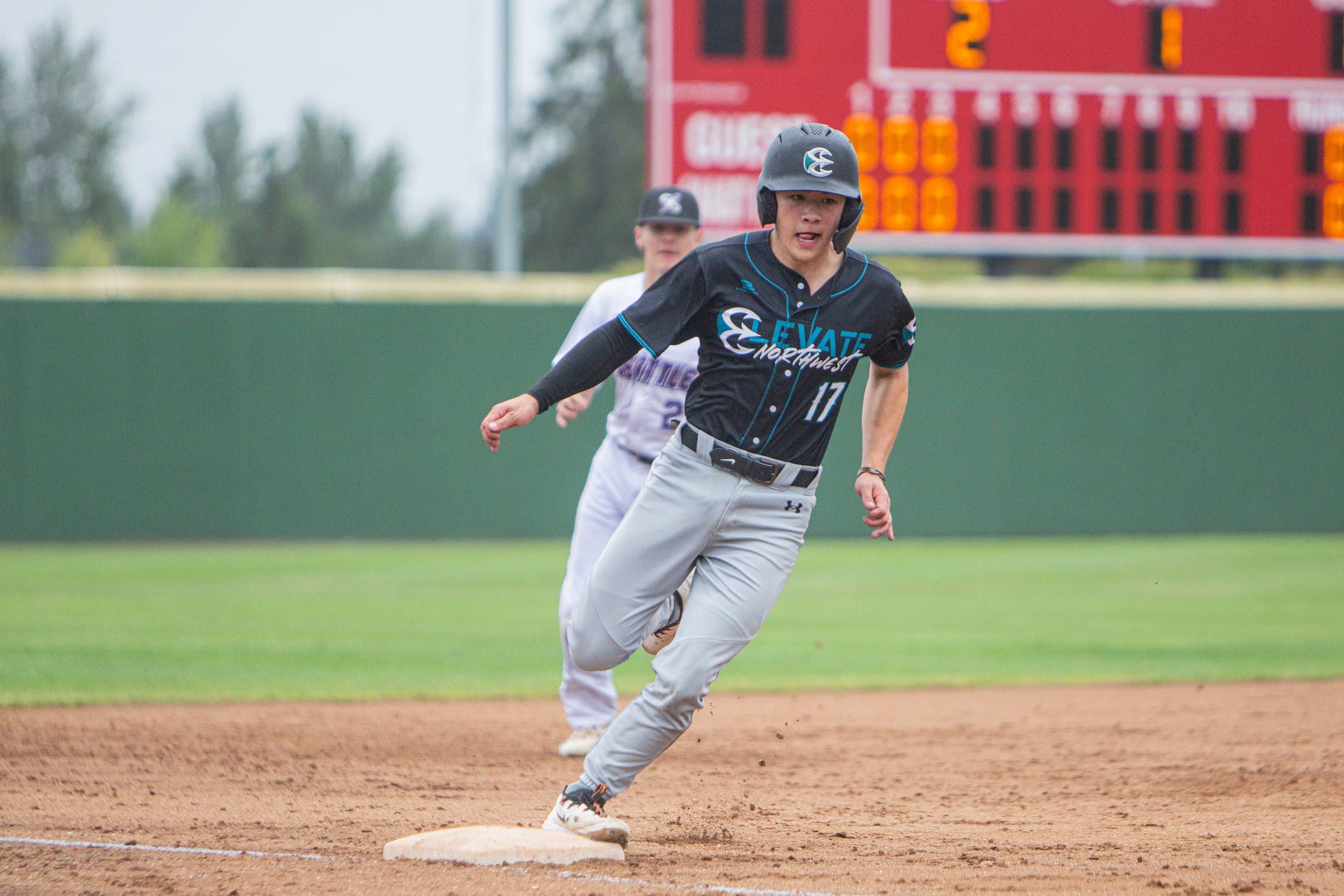 Runner rounding the bases with the scoreboard behind him