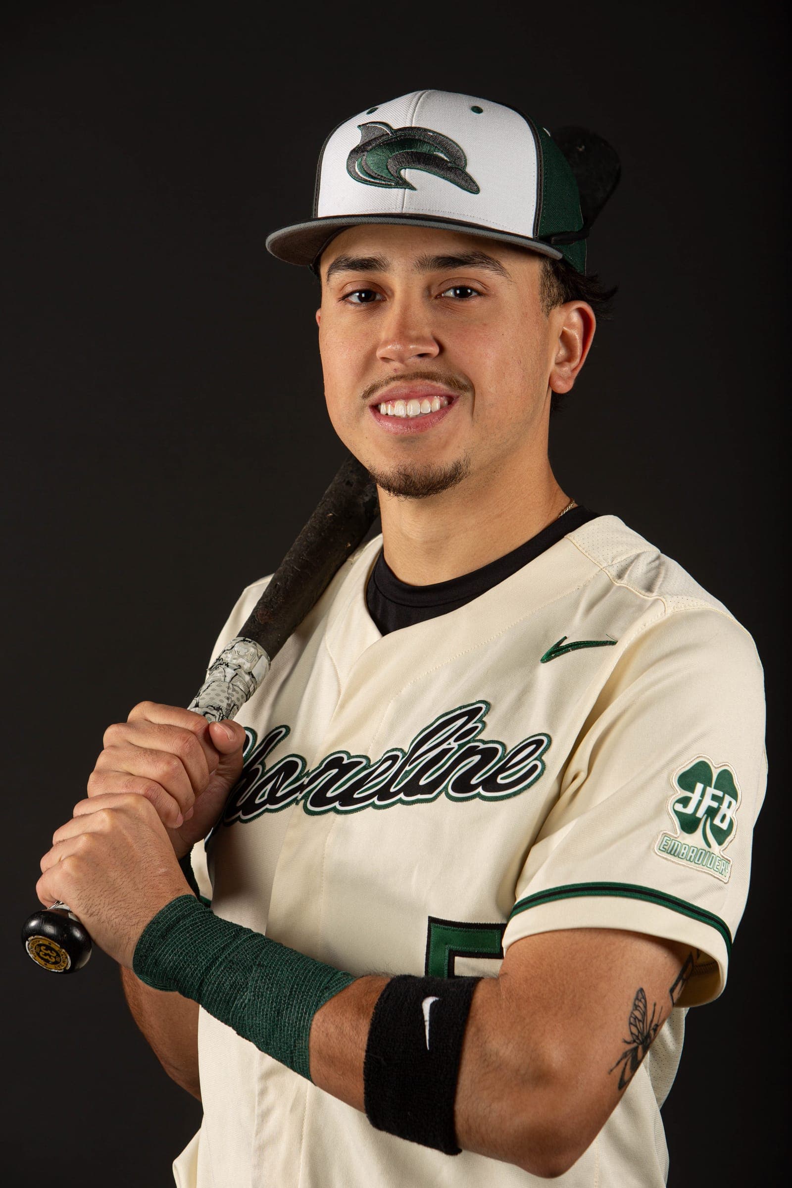 Shoreline player gripping his bat and smiling in dramatic side light