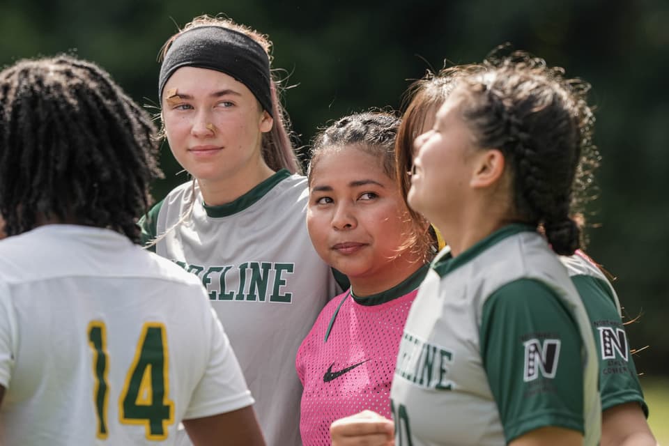 Shoreline women’s soccer players standing together in a huddle on the sideline
